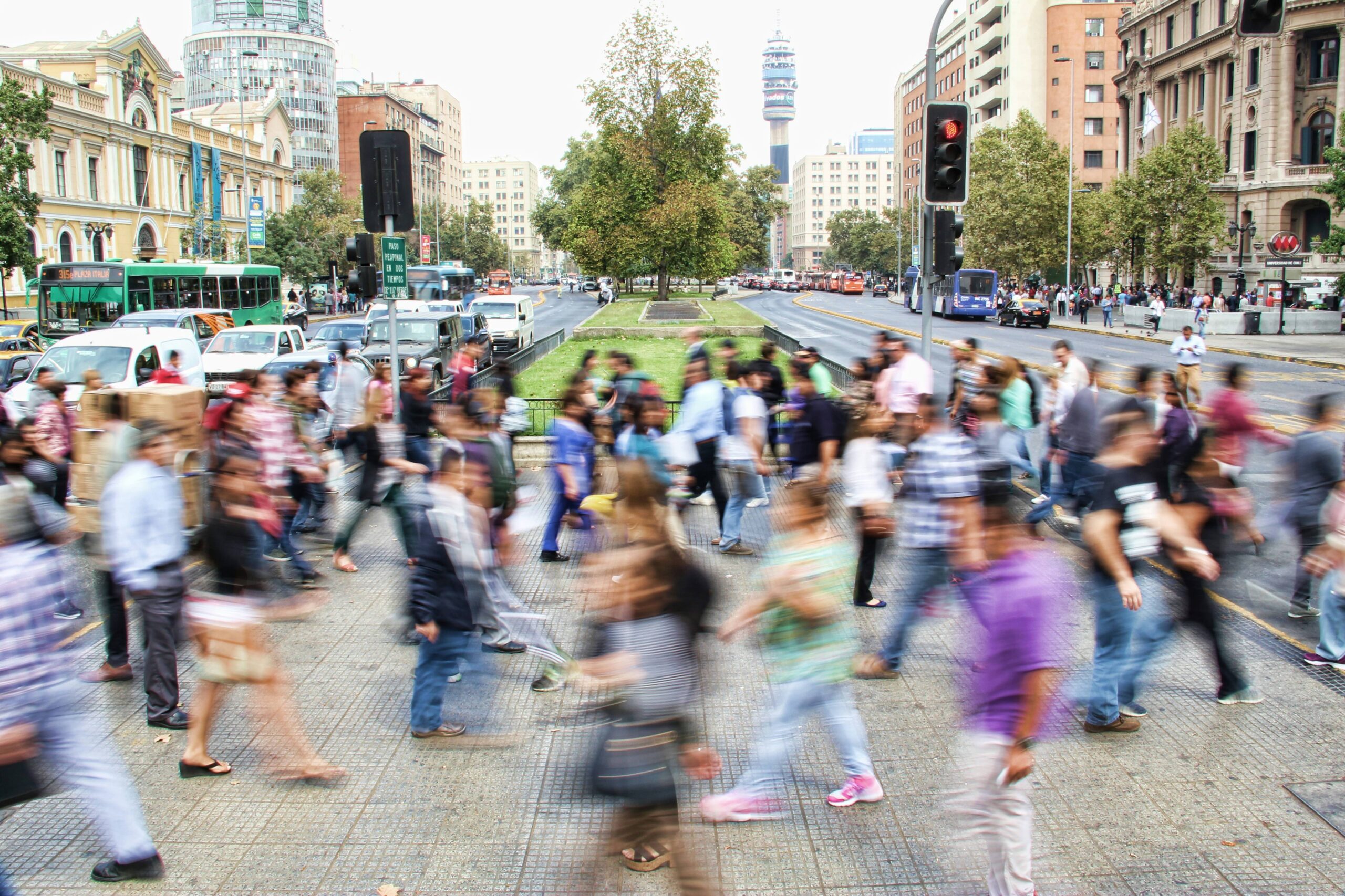 An image of a crowd of people walking across a streetscape. The people are blurred.