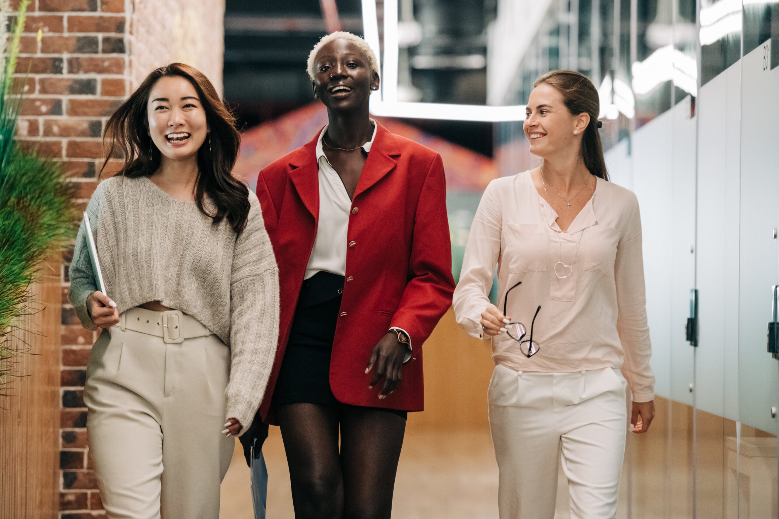 Three corporate women walking together through a modern office building