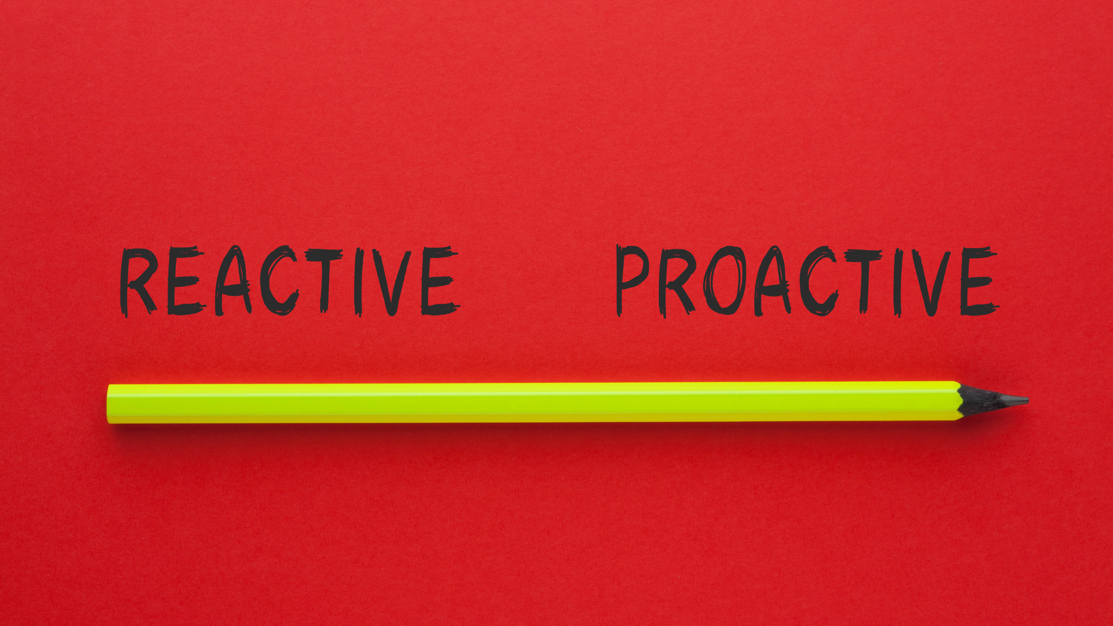 Yellow pencil laying horizontal below the words 'reactive' and 'proactive' written in black, on a red background.