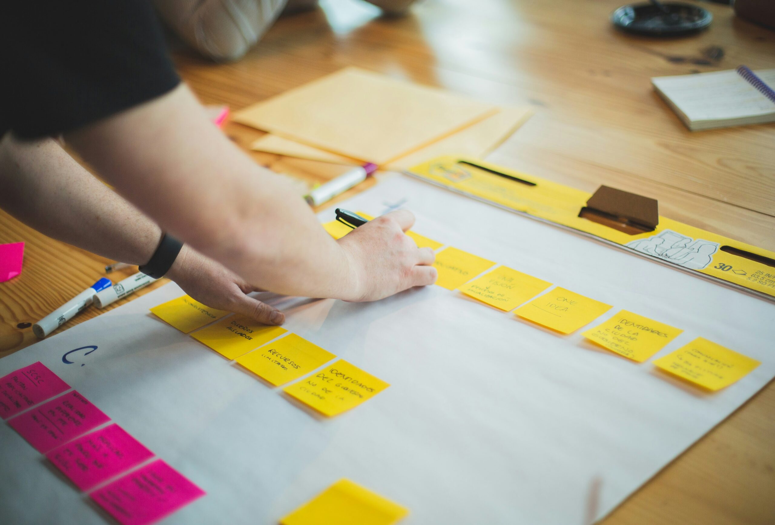 Person organising colourful sticky notes and planning resources on a desk